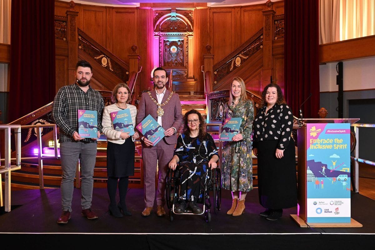 Several people standing in front of a nice staircase holding awards, one of them in a wheelchair. 